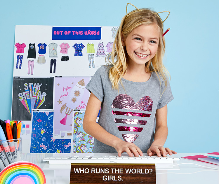 Photo of girl typing on the keyboard wearing a cute gray shirt with a heart design made of sequins